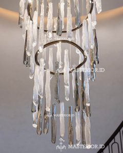 White fringe spiral chandelier in modern living room — custom lighting Jakarta. Modern cascading crystal chandelier with suspended hand-blown glass elements and brushed brass accents.